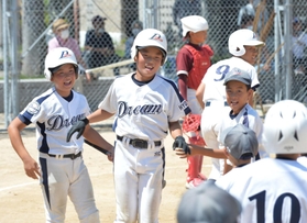 加古川ｂｂドリーム－播磨少年クラブ　三回表、本塁打を放って仲間に迎えられる岩井蓮選手（中央）。四回にも連続となる本塁打を決めた＝神戸市西区岩岡町岩岡、ＣＣＰグラウンド