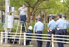 電源中継箱を使った信号機の復旧作業を確認する加古川署員＝加古川市平岡町新在家