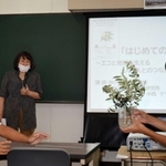 生徒にオリーブの実物を示しながら、歴史や用途について解説する中西テツさん（中央）＝東播工業高校