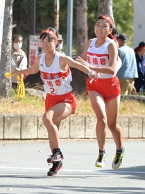 女子・東播磨の１区坂本幸妃音選手（右）からたすきを受け取り、走りだす２区の西尾わこと選手＝西脇市総合市民センター（撮影・笠原次郎）
