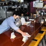 開店に向け、間仕切りが設けられたカウンターをアルコールで拭く藤沢大祐さん＝加古川市平岡町新在家２