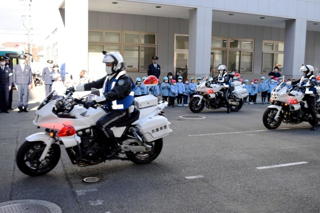 幼稚園児に見送られ、白バイで出発する署員ら＝加古川市平岡町新在家