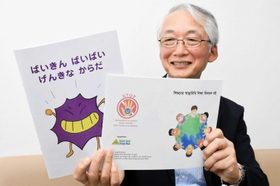 手洗いの大切さなどを解説した日本語の絵本（左）とバングラデシュ版を持つ山庄司志朗さん＝加古川市平岡町新在家、日の出医療福祉グループ