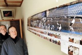 昨年１２月に集まったコウノトリ６４羽の写真を自宅に飾る金沢正己さん（左）と細工所ため池協議会会長の前田茂男さん＝加古川市志方町細工所