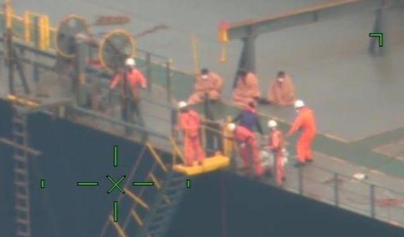 海を見下ろすムーンライト・ドルフィンの乗組員と毛布にくるまる要救助者（第１１管区海上保安本部提供）