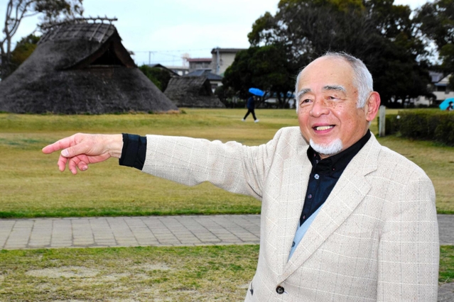 復元された竪穴住居前で、６０年前の様子を振り返る浅原重利さん＝播磨町大中１