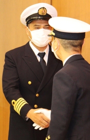 人命救助に貢献したとして、第１１管区海上保安部の一條正浩本部長と握手するノルベルト・アンソン・コルモ・ジュニア船長＝加古川市金沢町、神戸製鋼所加古川製鉄所