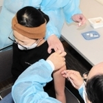 ワクチン接種を受ける１１歳児童。小児科医が問診、接種を担当する＝加古川市役所