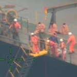 海を見下ろすムーンライト・ドルフィンの乗組員と毛布にくるまる要救助者（第１１管区海上保安本部提供）