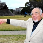 復元された竪穴住居前で、６０年前の様子を振り返る浅原重利さん＝播磨町大中１