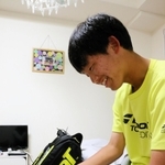 激しい練習を終え、寮で両親と携帯のテレビ電話で会話する副主将の高畑里樹さん。壁には東京のテニス仲間が書いてくれた寄せ書きが掛かる＝加古川市内