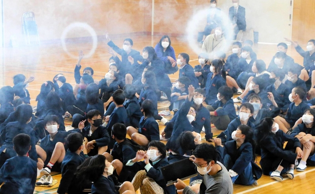 巨大空気砲から放たれた白い輪を見上げる子どもたち＝阿弥陀小学校