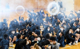 巨大空気砲から放たれた白い輪を見上げる子どもたち＝阿弥陀小学校