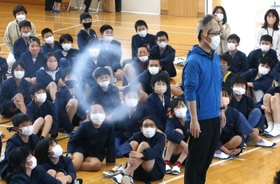 かつらをかぶった教諭に向けて放たれた白い輪を見つめる児童ら＝阿弥陀小学校
