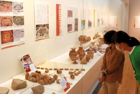 弥生時代の集落遺跡からの出土品が並ぶ展示会場＝県立考古博物館