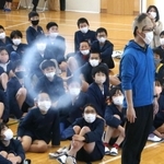 かつらをかぶった教諭に向けて放たれた白い輪を見つめる児童ら＝阿弥陀小学校