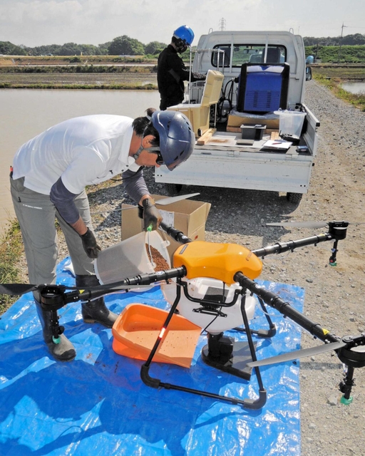 特殊なコーティングをした種もみをドローンに補充する共同防除隊のメンバー＝加古川市八幡町上西条