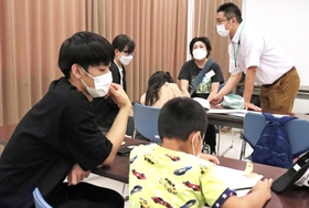宿題を教えるボランティアと、熱心に宿題に取り組む児童＝平岡公民館