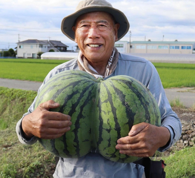 収穫したスイカを持つ北川史朗さん＝稲美町