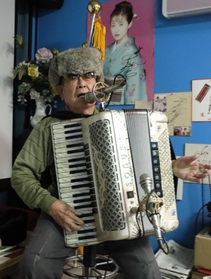 アコーディオンで戦争体験を歌い継ぐ田中唯介さん。ロシア製の防寒帽は、友好の願いを込めてかぶっているという＝高砂市