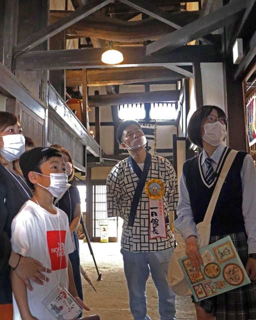参加者とともにボランティアガイドの説明を受ける吉田裕さん（中央）＝工楽松右衛門旧宅