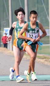 男子・浜の宮の３区甲斐健斗選手（左）からたすきを受け取って駆け出す４区七條拓也選手＝豊岡市日高町（撮影・長嶺麻子）