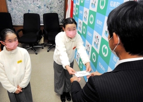 中山哲郎町長にこどものまちへの招待状を渡すこども町長の吉村碧華さん（中央）と、副町長の緋華さん＝稲美町役場