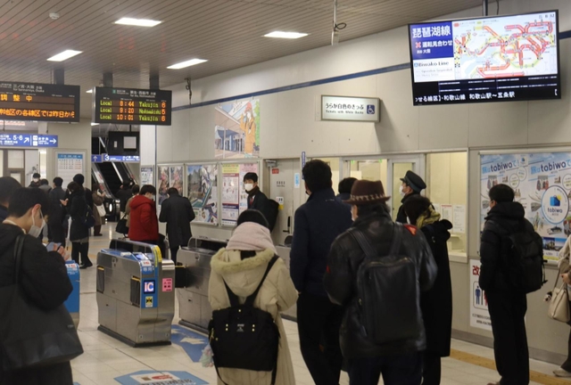 通勤や通学のため、駅の掲示板で運行状況を確認する人々＝２５日午前８時３２分