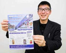 「加古川まつかぜハーフマラソン」のチラシを手に、笑顔を見せる神屋伸行さん＝加古川市加古川町粟津