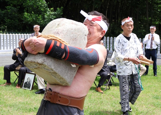 力石の持ち上げを成功させる瀬川喜樹さん＝鹿嶋神社