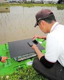 スマホでアイガモロボを起動させる井関農機の担当者＝加古川市八幡町