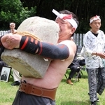 力石の持ち上げを成功させる瀬川喜樹さん＝鹿嶋神社