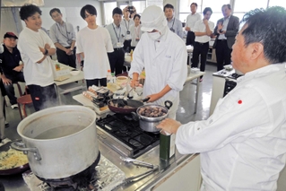 独自の料理論を伝えながら調理を進める奥田政行シェフ（手前右）。県農生が助手を務めた＝加古川市平岡町新在家