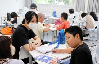 学生スタッフが子どもたちの宿題をお手伝い。多い日で子どもは４０人以上が集まるという＝加古川市平岡町新在家、兵庫大学