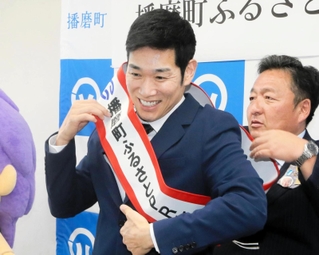 佐伯謙作町長（右）からたすきをかけてもらうレイザーラモンＨＧこと住谷正樹さん＝兵庫県播磨町東本荘１、播磨町役場