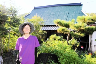 かやぶき民家の前に立つ住人の女性＝加古川市志方町成井