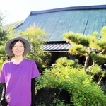 かやぶき民家の前に立つ住人の女性＝加古川市志方町成井