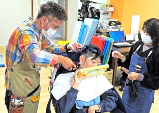 エアクリッパーで手早くカットする安大さん。吸引するため施設内に髪の毛が散乱しない＝加古川市加古川町大野