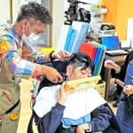 エアクリッパーで手早くカットする安大さん。吸引するため施設内に髪の毛が散乱しない＝加古川市加古川町大野