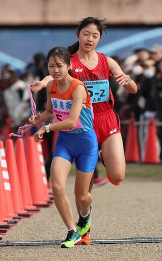 女子・加古郡の２区吉川菜緒選手（右）からたすきを受ける３区角侑哩選手＝加古川市の加古川河川敷マラソンコース（撮影・笠原次郎）