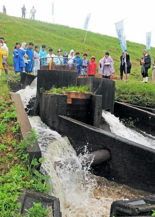 神事の後、「円筒分水工」から水が流れ出し、歓声を上げる児童たち＝加古川市志方町原