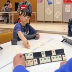 頭をひねり、タイルを並べる選手たち＝加古川市民会館