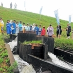 神事の後、「円筒分水工」から水が流れ出し、歓声を上げる児童たち＝加古川市志方町原