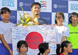 子どもらからの寄せ書きを手にするディーン元気選手（中央）＝加古川運動公園陸上競技場