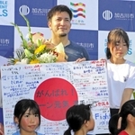 子どもらからの寄せ書きを手にするディーン元気選手（中央）＝加古川運動公園陸上競技場