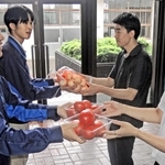 自分たちが育てた野菜を兵庫大生（右の２人）に手渡す県農生。規格外などの理由で廃棄する予定だった＝県立農業高校