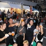 「乾杯」の音頭を弾ませ、笑顔で飲み交わす来場者＝播磨町役場前