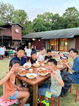 手作りピザを味わう兵庫大学生らと珠洲市の子ども＝川西市内のキャンプ場（主催者提供）