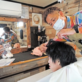 移動美容室で施術する安大陽平さん。２号車製作に向け支援を募る＝加古川市加古川町