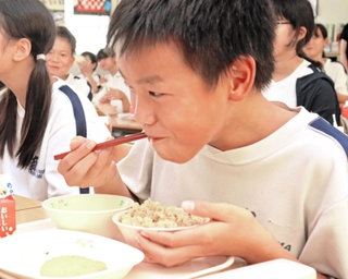 播磨町の食材を使った「たこめし」を頰張る児童＝播磨南小学校